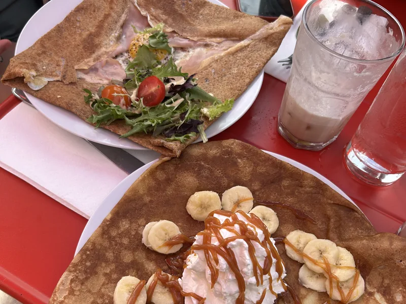 A savoury buckwheat galette with ham and egg beside a banana-caramel sweet crêpe on the red patio at Paris Crêpes Café, Niagara Falls