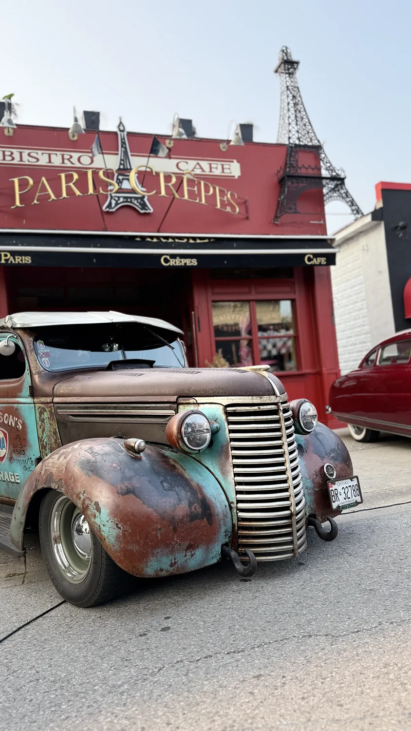 A vintage hot rod parked outside Paris Crêpes Café during a car night on Queen Street, Niagara Falls