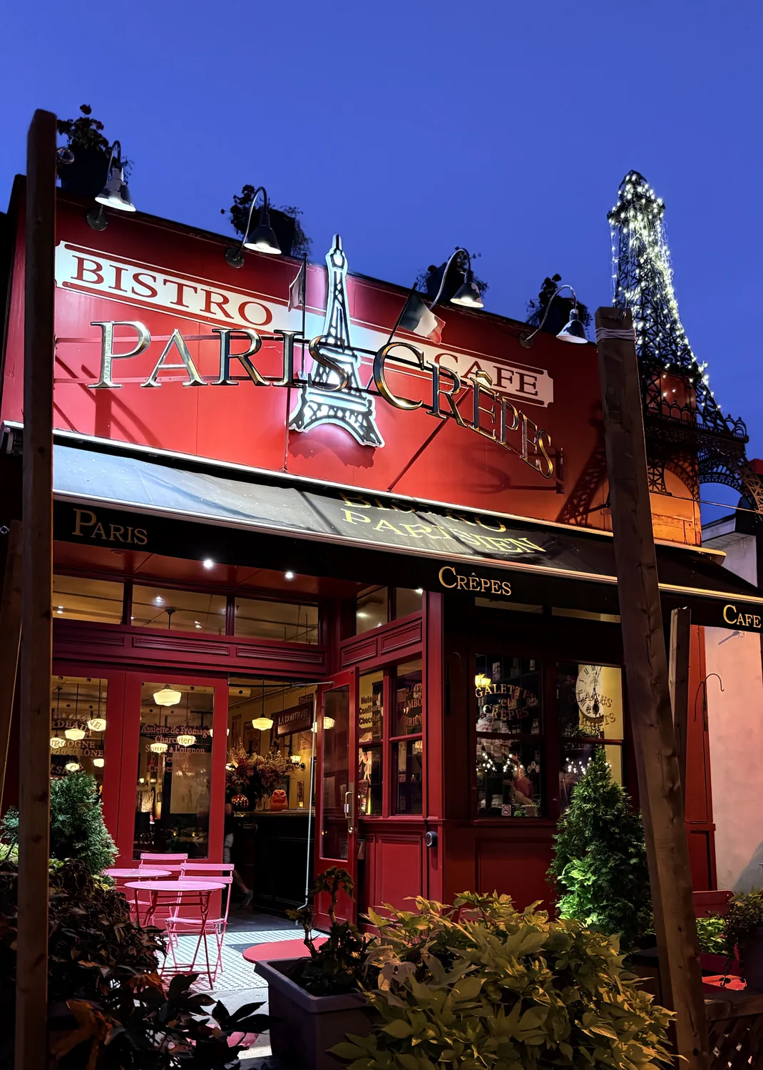 Paris Crêpes Café lit up at dusk on Queen Street, Niagara Falls, with the Eiffel Tower sign in lights